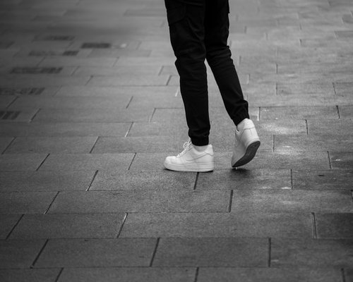 A person wearing comfortable shoes walking on a pavement